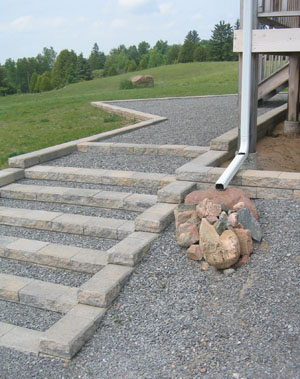 Less is more. A granite stone arrangement prevents washout and sets off well against warm grey interlocking steps. The gravel base might be paved later as funding permits
