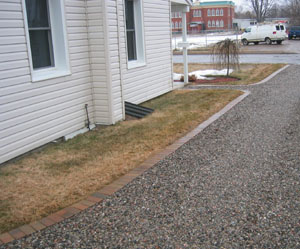 Parked cars will eventually create ruts in any driveway unless great care is spent on subgrade, so when you have a big driveway, consider a "soldier course of elegant brick separating the lawn and the gravel. 